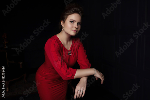 portrait of young female in red dress dark background