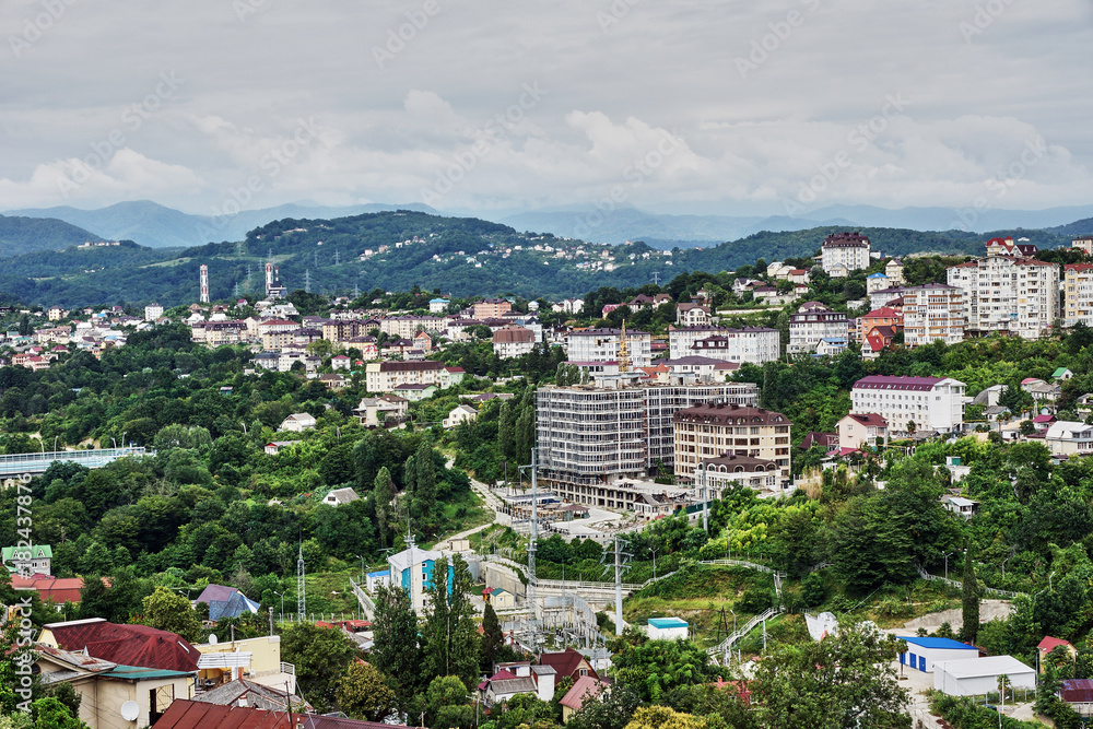 Obraz premium Panorama of the city of Sochi from a bird's eye view/Panorama of Sochi from the air. Houses, streets, trees, the sky are visible. In the distance you can see the sea. Sochi, Russia, cityscape