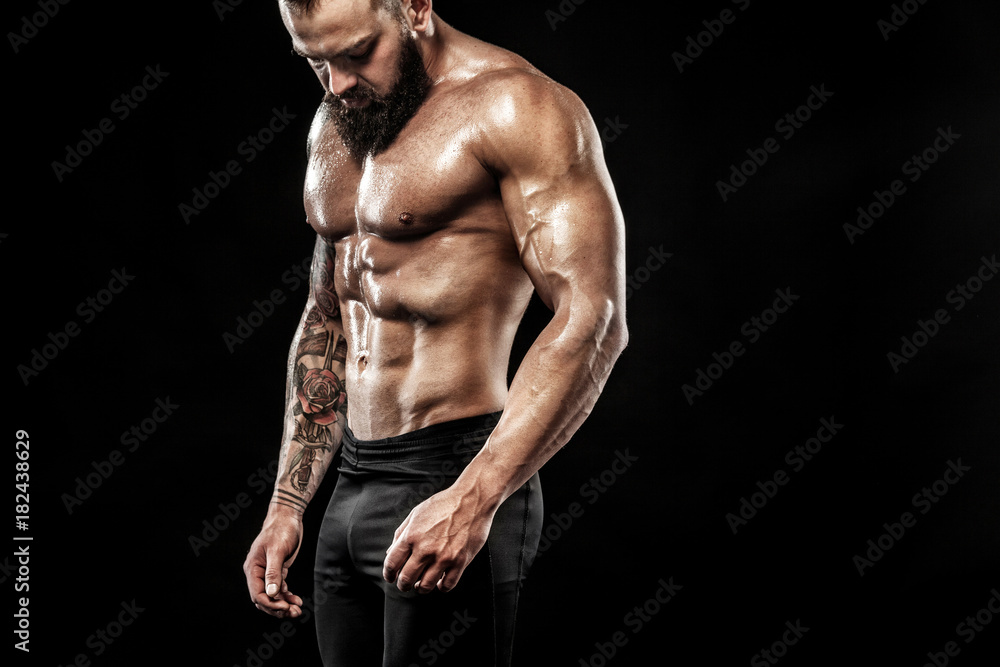 Handsome fit man posing wearing in jeans with tattoo. Sport and fashion concept isolated on black background.