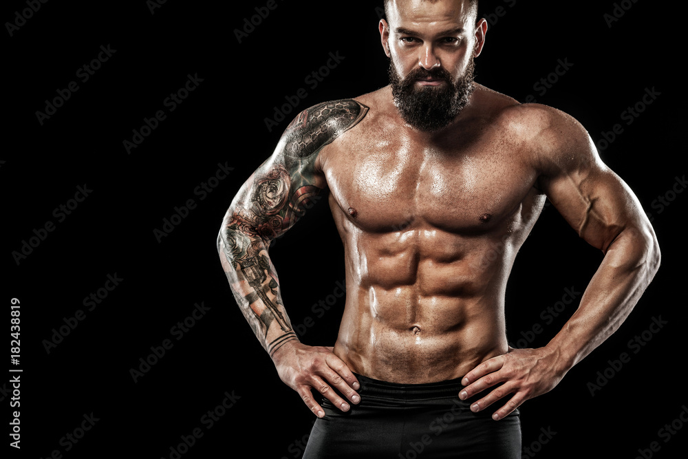 Handsome fit man posing wearing in jeans with tattoo. Sport and fashion concept isolated on black background.