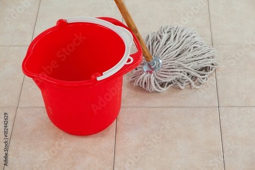 Empty bucket and mop on tile floor