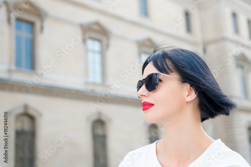 Girl with red lips in sunglasses pose on city street