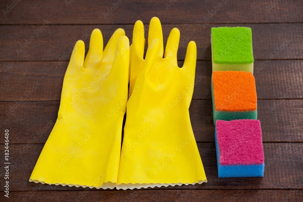 Glove and scrubber arranged on wooden floor Glove and scrubber arranged on wooden floor