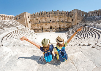 Two young girls student traveler enjoy a tour of the ancient Greek amphitheater