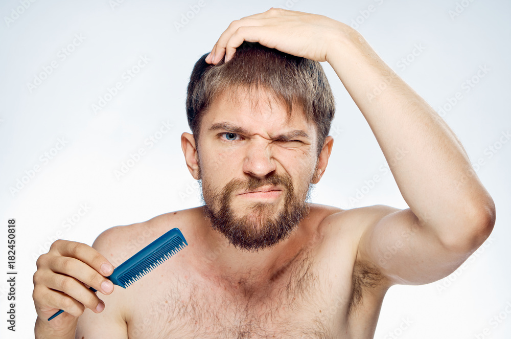 Obraz premium Man with a beard on a white isolated background holds a comb, portrait, emotions
