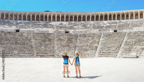 Two young girls student traveler enjoy a tour of the ancient Greek amphitheater