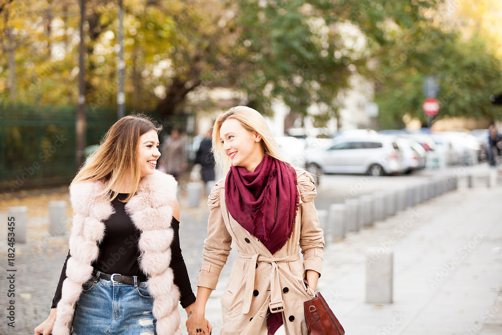 Two beautiful best friends women in the city walking on the road, smiling and having fun. Friendship and style