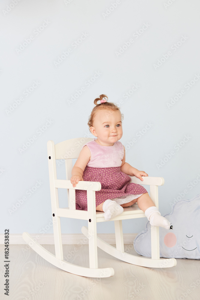 beautiful little girl in a dress sits on a white chair beautiful little girl in a dress sits on a white chair
