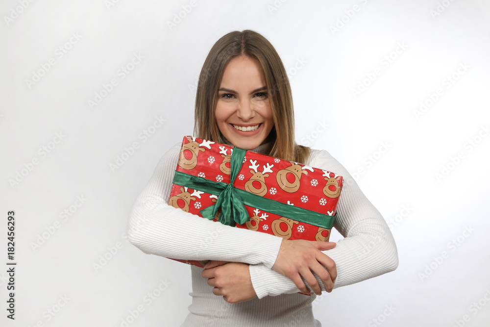 Hübsche blonde Frau hält ein Weihnachtsgeschenk in den Armen und lacht Hübsche blonde Frau hält ein Weihnachtsgeschenk in den Armen und lacht