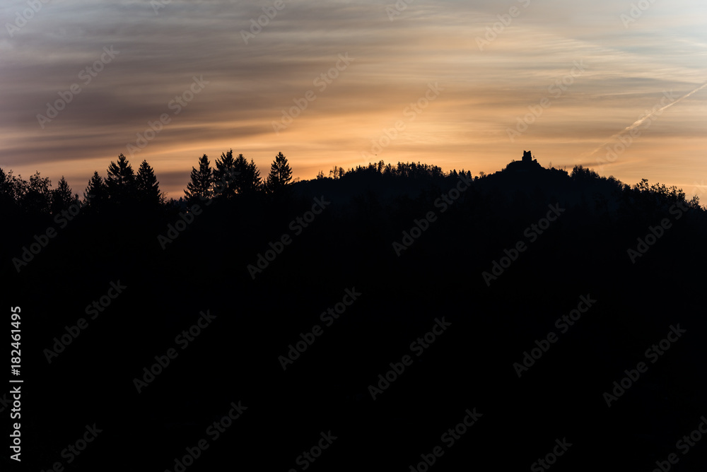 Old ruins on a forested mountain silhouetted