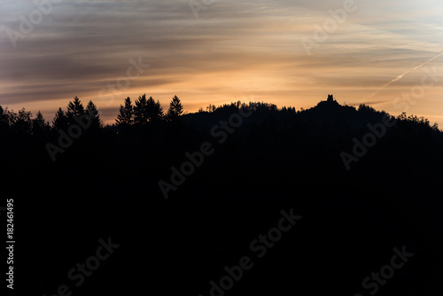 Old ruins on a forested mountain silhouetted