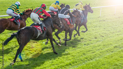 Race horses and jockeys racing towards the finish line with lens flare effect background
