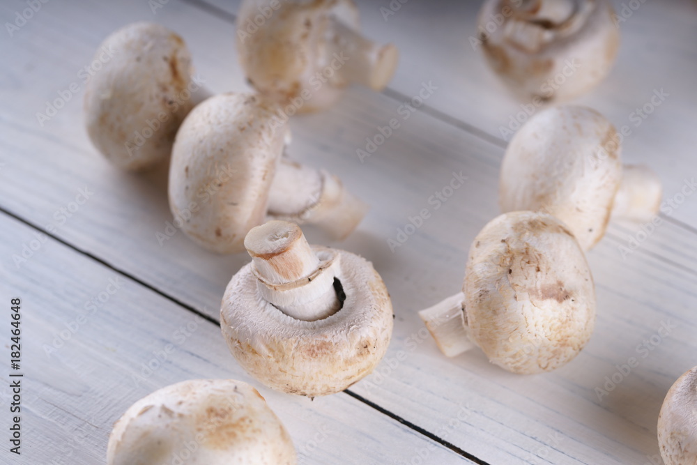 Mushrooms champignons on a white wooden background