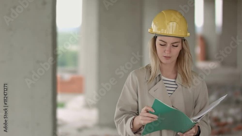 Young female architect construction engineer at a construction site eximaining documents photo