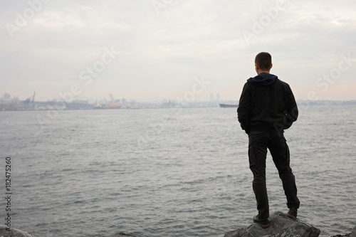 Man standing near the sea and looking at horizon  cloudy windy day. Thinking  Concentration  Loneliness concept.