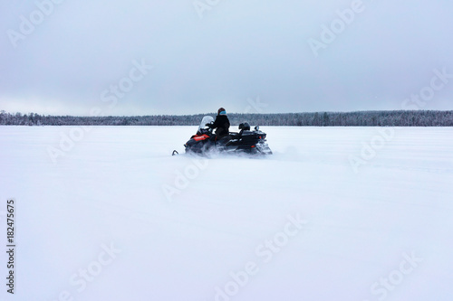 Woman driving snowmobile on frozen lake at winter Rovaniemi Finland