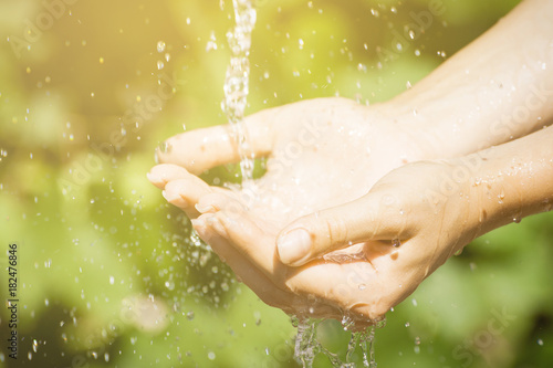 Woman washing hand outdoors. Natural drinking water in the palm. Young hands with water splash, selective focus