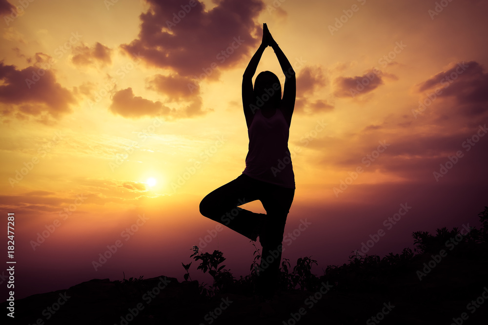 Woman training yoga on the mountain at sunset
