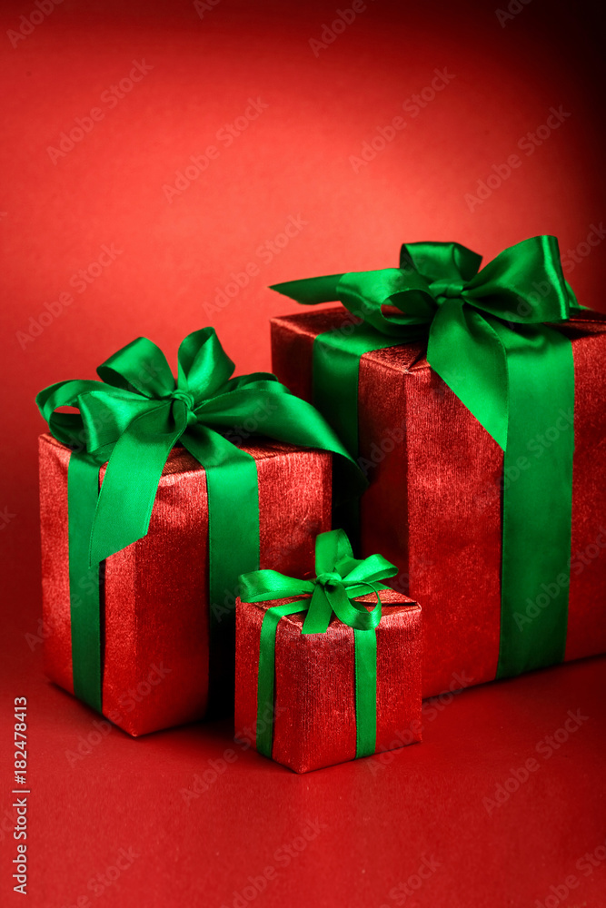 Obraz premium Red gift boxes with green ribbons and bow on red holiday background . Merry christmas card. Winter xmas theme.Boxing day