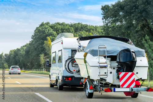 Caravan and trailer for motor boats on road in Switzerland