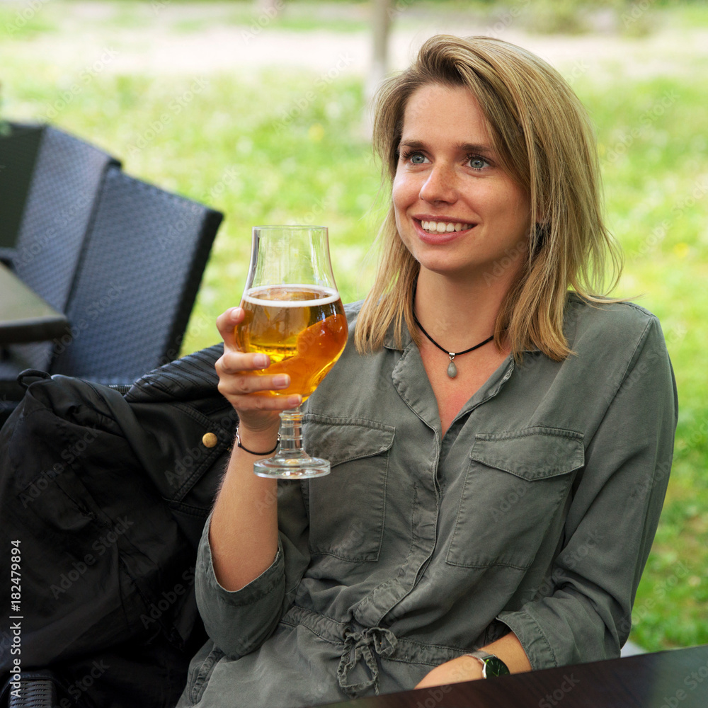 Young smiling woman drinking glass of beer in street restaurant Young smiling woman drinking glass of beer in street restaurant