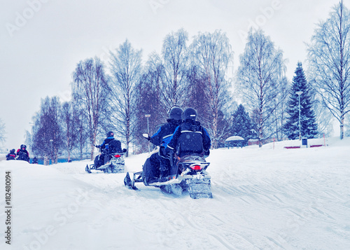 Men and women riding snowmobiles at winter Rovaniemi