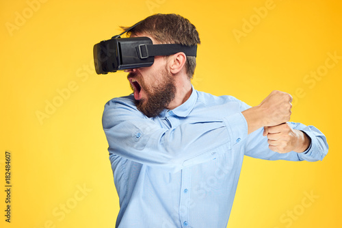 A man with a beard on a yellow background in glasses of virtual reality, entertainment
