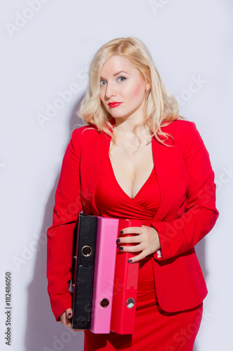 Portrait of a beautiful young blonde woman in a red business suit. The girl holds a folder for documents photo