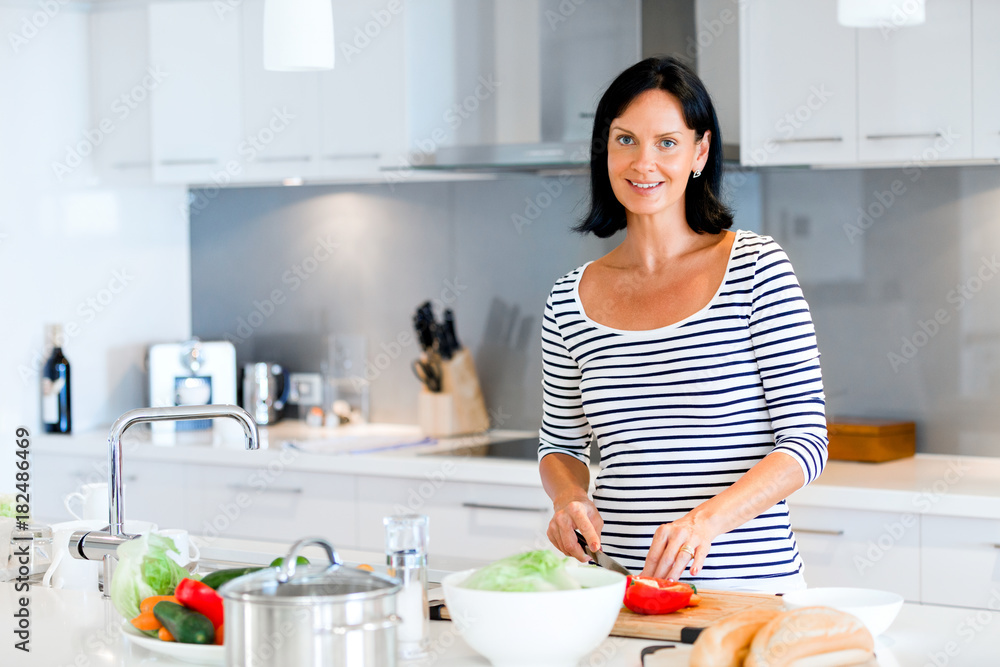 Beautiful woman standing in the kitchen and smiling Beautiful woman standing in the kitchen and smiling