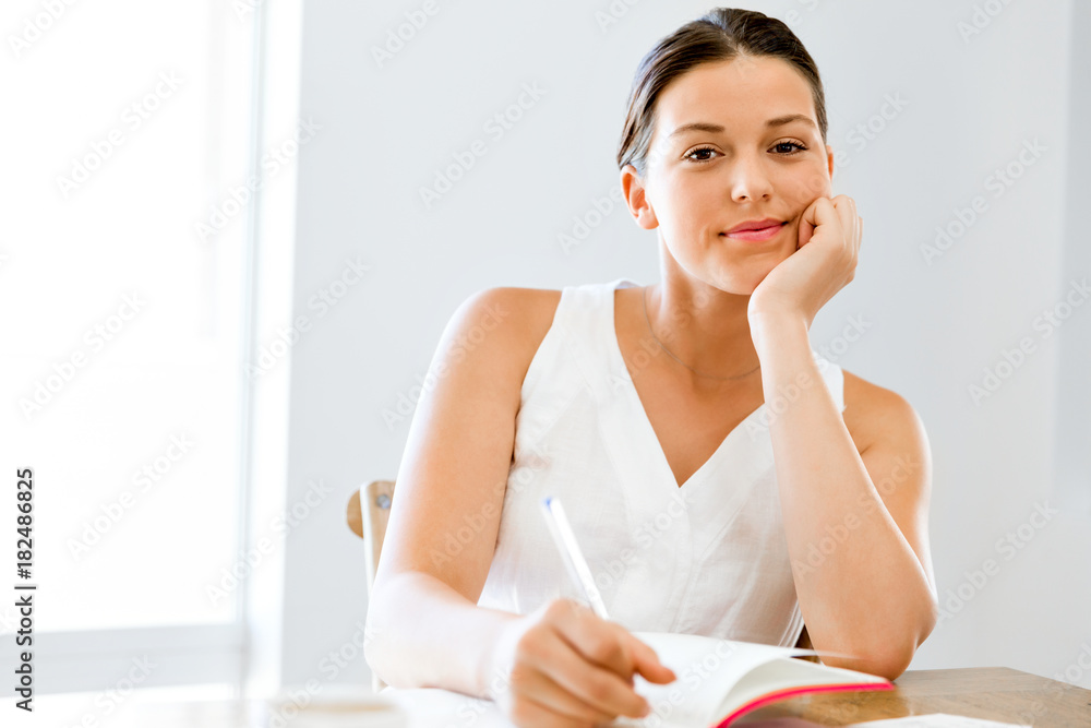 Young woman writing in an agenda at home or office Young woman writing in an agenda at home or office
