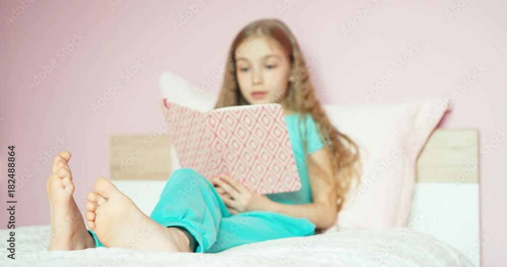 Cheerful child girl closed notebook on the bed and laughing at camera Cheerful child girl closed notebook on the bed and laughing at camera