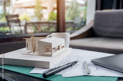 An architects designed architecture model with shop drawing paper and laptop on table © Farknot Architect