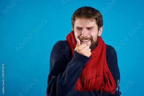 Man with a beard on a blue background, scarf, sweater, flu, sickness, empty space for copy, portrait