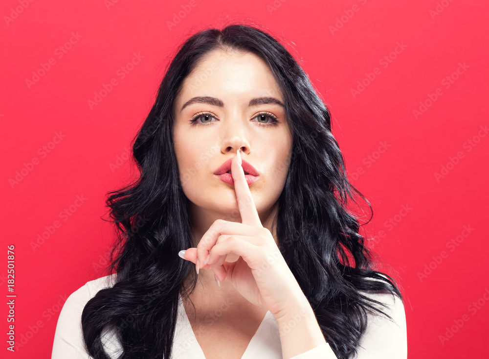 Young woman making a quiet gesture on a solid background Young woman making a quiet gesture on a solid background
