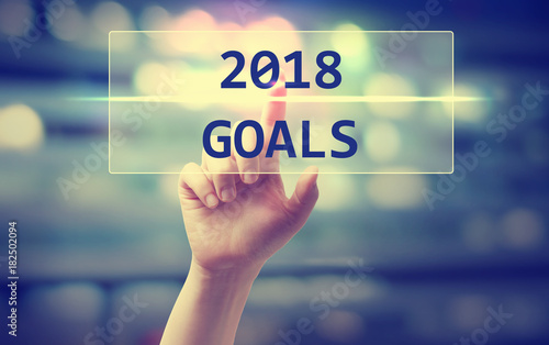 2018 Goals concept with hand pressing a button on blurred abstract background