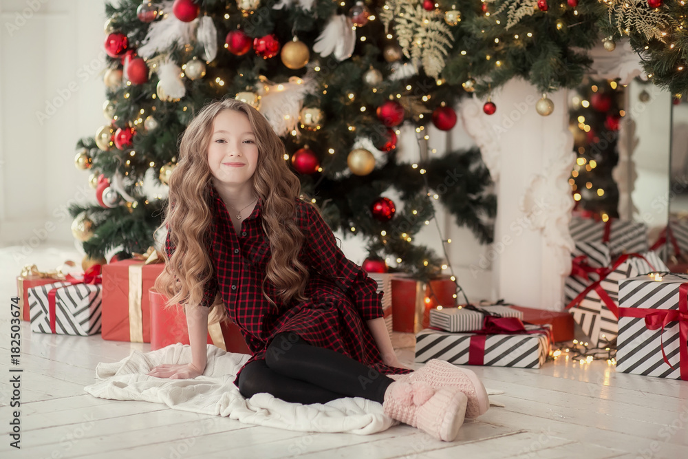 Smiling girl sitting under Christmas tree Smiling girl sitting under Christmas tree