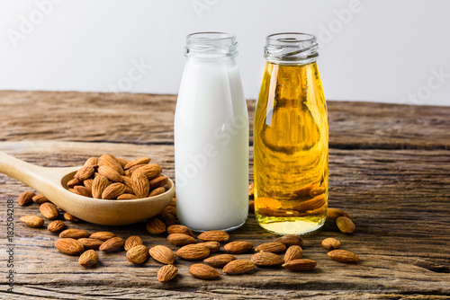 Peeled almonds with bowl and Bottle of almond milk and oil on rustic wooden