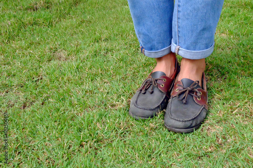 Fashion Man is Legs in Blue Jeans and Wear Vintage Shoes on Green Grass Background Great for Any Use.