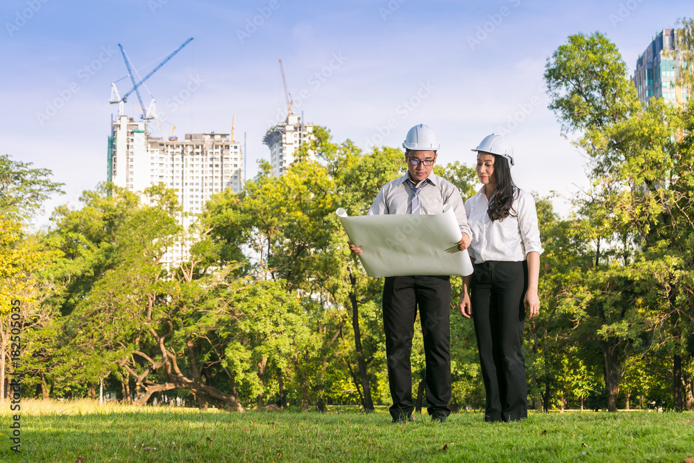 Couple civil engineer smilling while checking plan in green park Couple civil engineer smilling while checking plan in green park