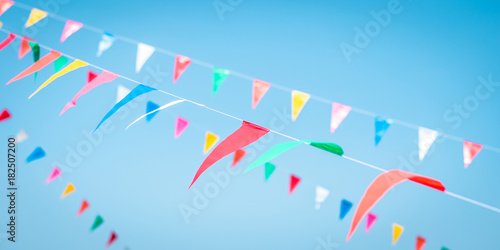 Fair flag blur bunting background hanging on blue sky for fun festa event, summer holiday farm feast, carnival festival event, park or street design decoration element 