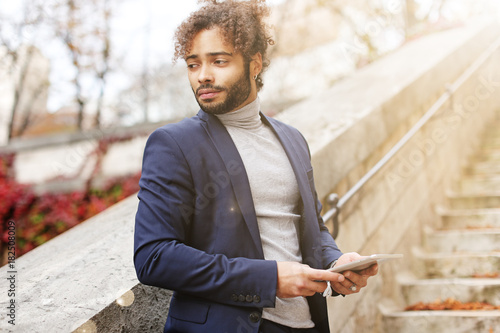 Handsome half Nigerian boy staying with tablet. photo