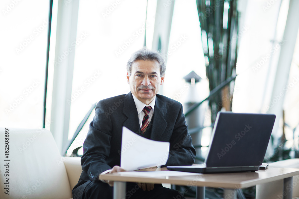 Confident businessman with documents on a laptop Confident businessman with documents on a laptop
