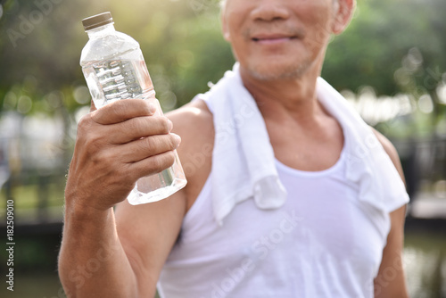 Asian senior male holding bottle of water.