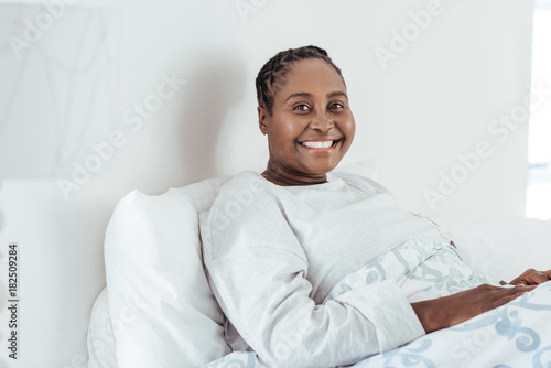 Smiling young African woman sitting up in her bed