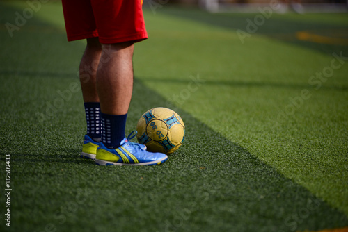 Unidentified group of male football players playing amateur football match on sunny summer day on simple sports venue