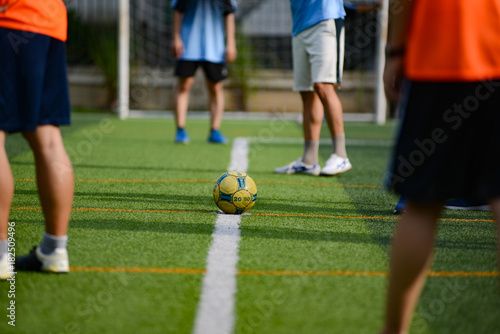 Unidentified group of male football players playing amateur football match on sunny summer day on simple sports venue