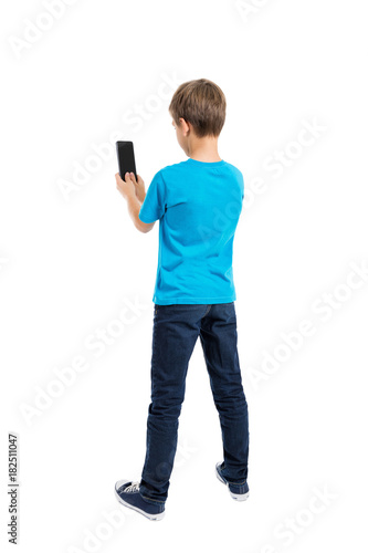 Back view of boy in t-shirt and jeans talking on mobile phone