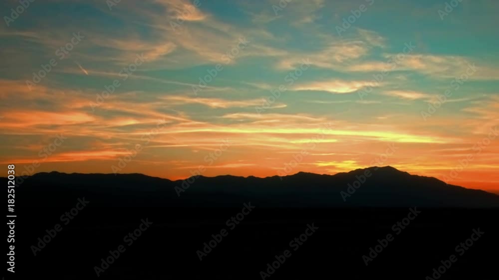 Panning aerial shot of mountains silhouetted against a red sunset Panning aerial shot of mountains silhouetted against a red sunset