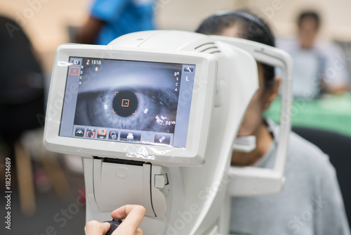 Woman looking at refractometer eye test machine in ophthalmology photo