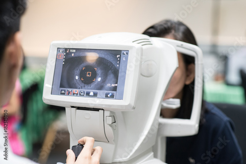 Woman looking at refractometer eye test machine in ophthalmology